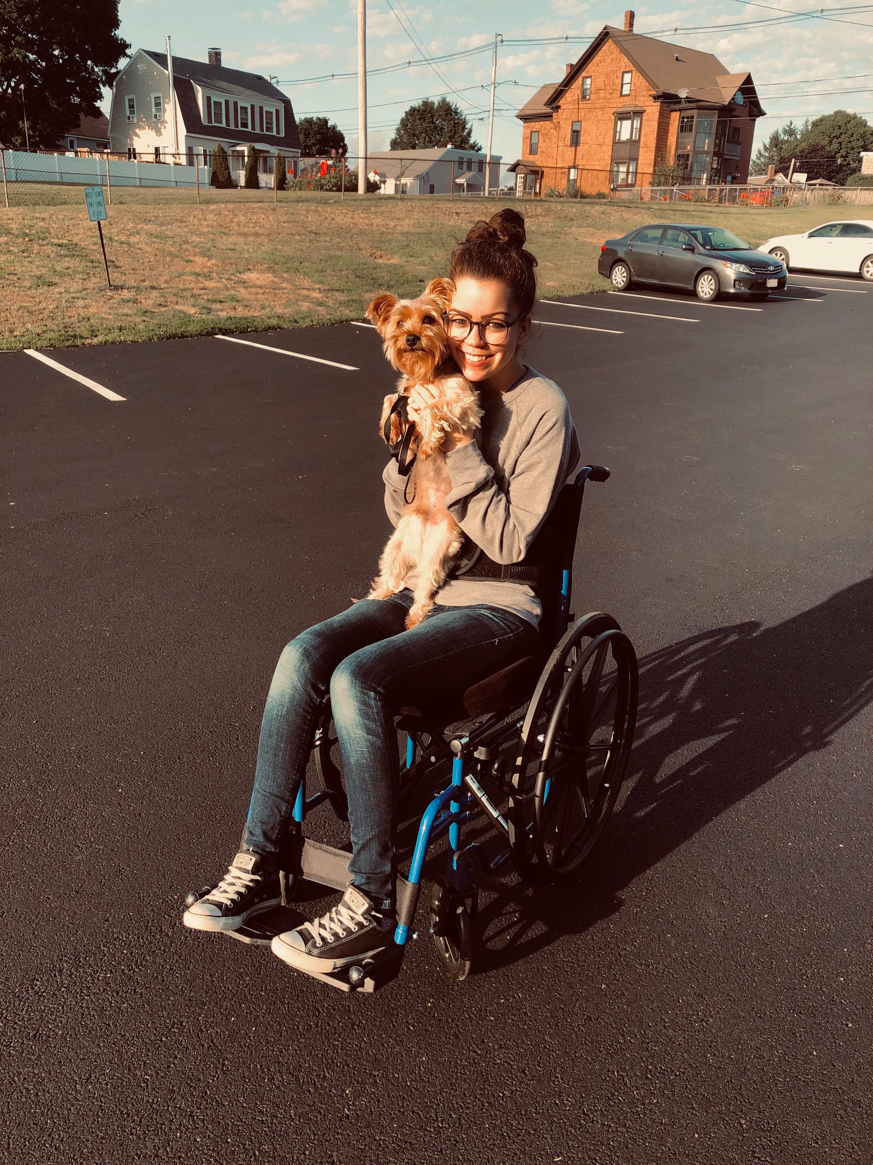 Jennifer in her wheelchair holding her small dog.