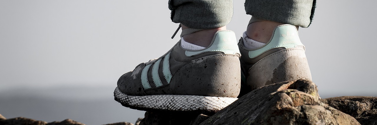 View of a person's tennis shoes as they stand on rocks.