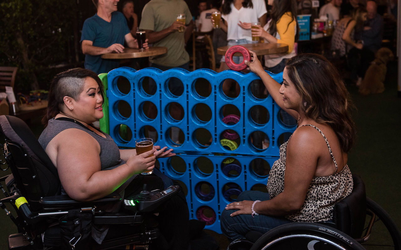 Two women who use wheel chairs playing an oversized game of Connect 4