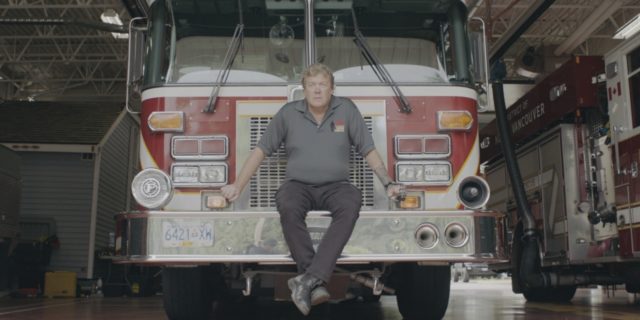 photo of retired firefighter Erik Bjarnason sitting on firetruck looking at camera