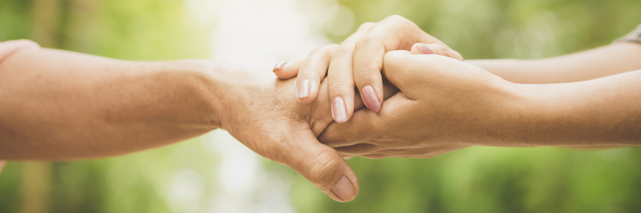 Avoiding Words Like 'Survivor' and 'Fight' With Breast Cancer close-up of a daughter holding her mother's hand outdoors over nature background