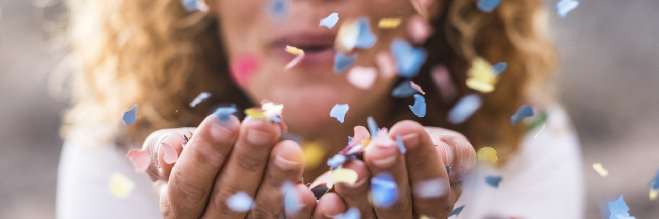 Woman cupping her hands and blowing confetti