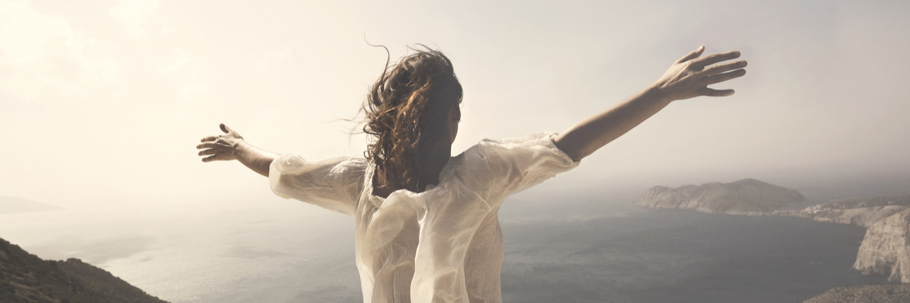 When Asking For Help Is Brave Woman raising her arms out in front of a spectacular view of mountains and ocean