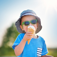 Happy child eating ice cream outdoors in summer.