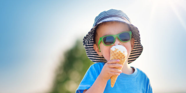 Happy child eating ice cream outdoors in summer.