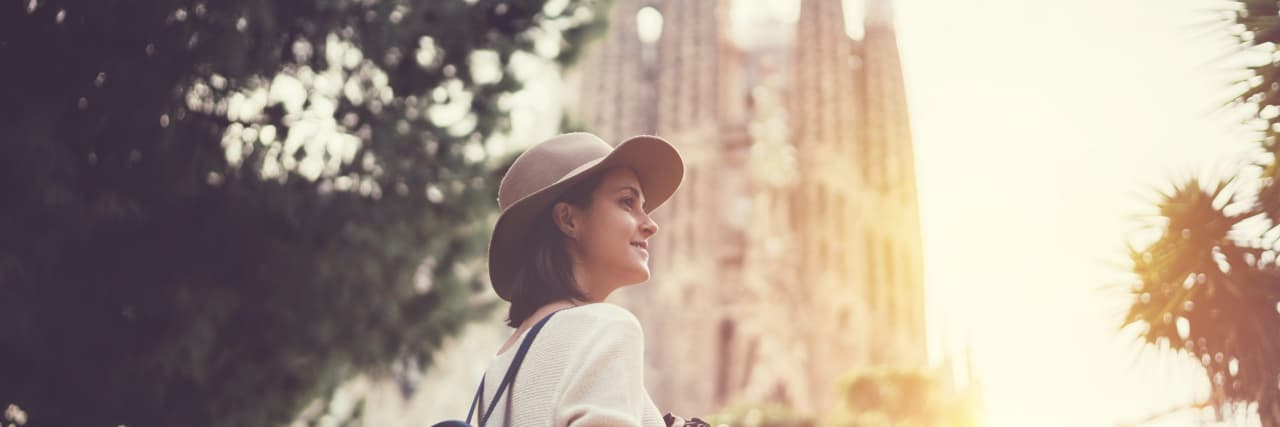 11 Tips for Traveling With Chronic Pain a woman standing in front of La Sagrada Familia in Barcelona, Spain