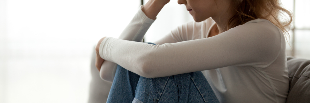 I Broke Down in Front of My Parents Because of Chronic Pain photo of young woman crying with knees raised to her chest