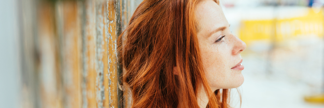 Being Afraid to Go to a Doctor Because of Mental Health Stigma A woman sits thoughtfully resting against a wooden background. against