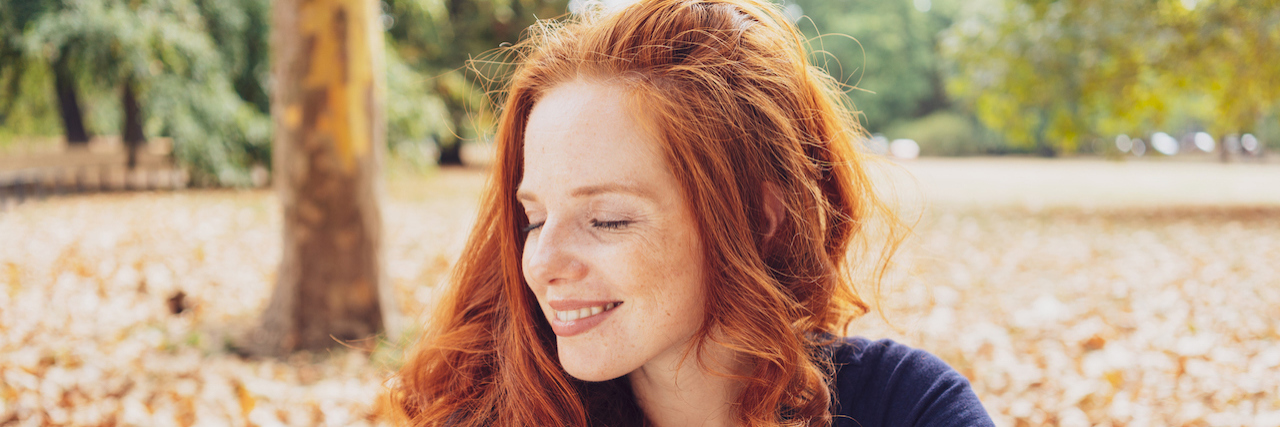 Forgiving Myself Can Help in My Struggle With Depression Woman relaxing in a park smiling