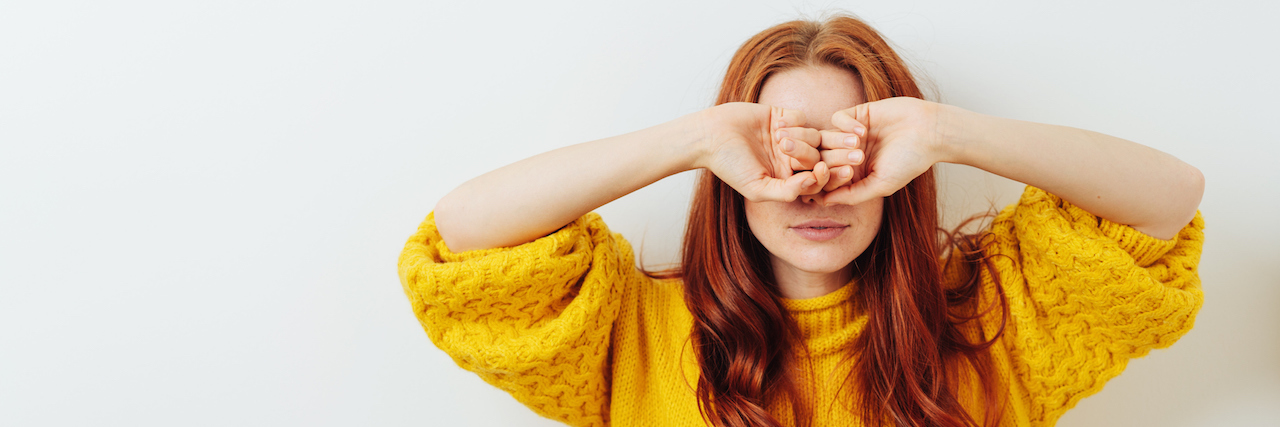Seeming 'OK' With Bipolar Disorder, Even When You're Not A young woman with her hands covering her face