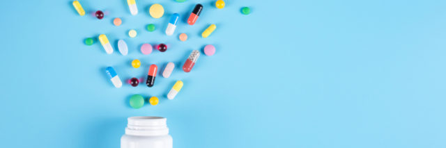 A bottle of colorful medication scattered individually across a blue background.