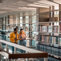 Two students talking about a book in the library