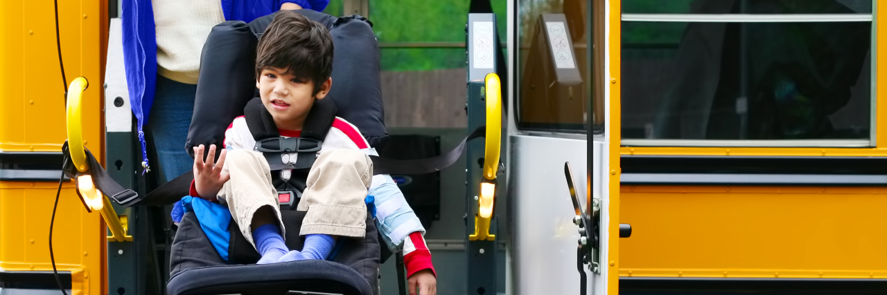 Boy in wheelchair on bus lift.