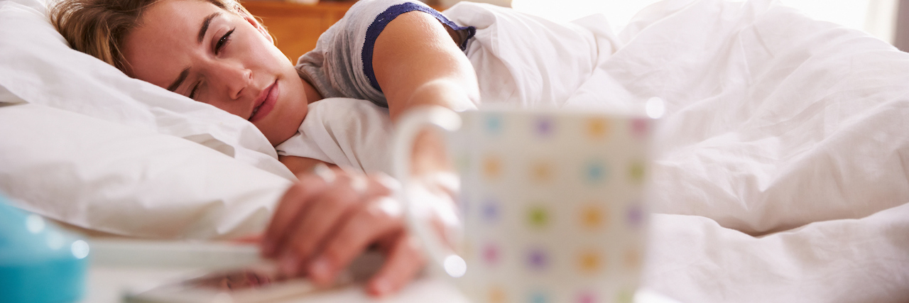 Getting Fired After Calling in Sick for Fibromyalgia A tired woman in bed, reaching for her phone