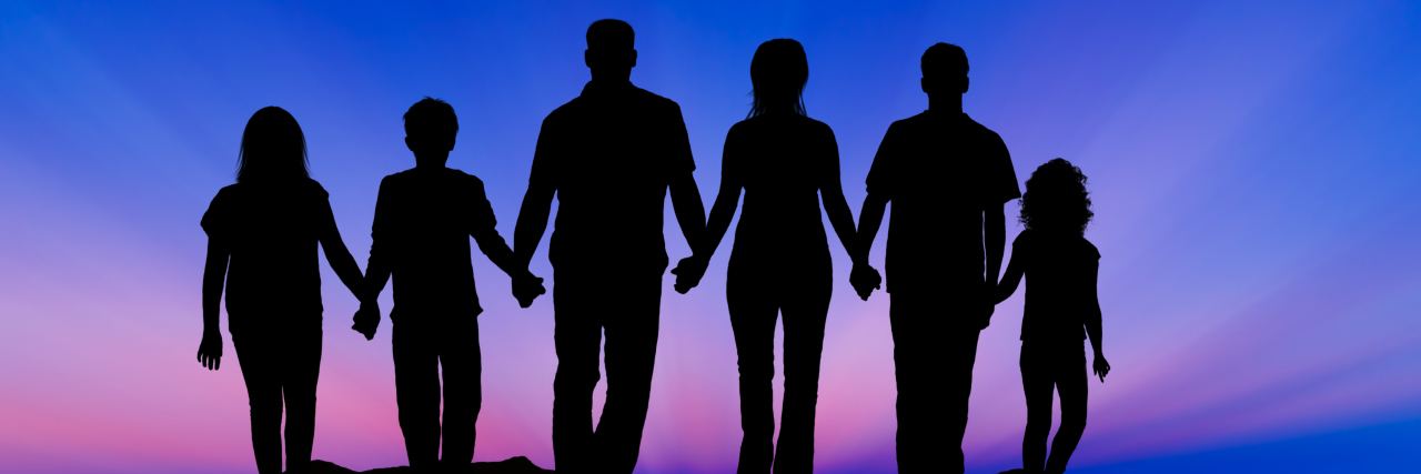 Silhouette of a family at sunset; everyone holding hands