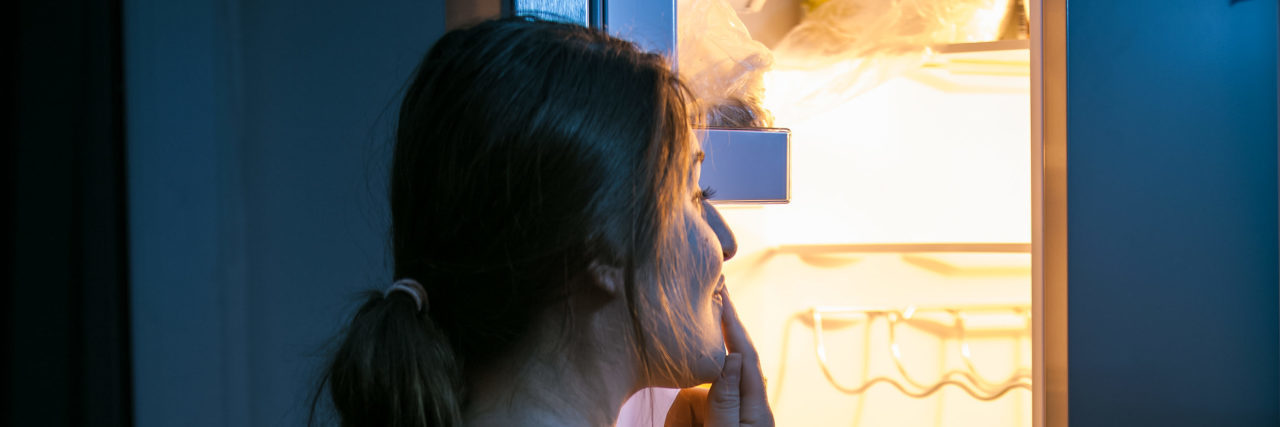 Dealing With a Sleep-Related Eating Disorder Sleepy woman looking in refrigerator.