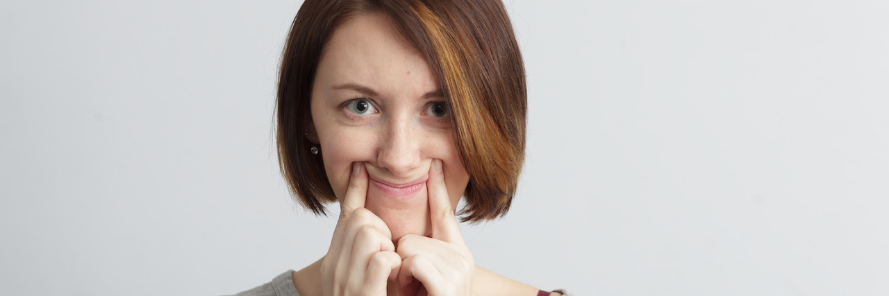 Pretending to Be Happy on Social Media Woman using her fingers to make her mouth smile