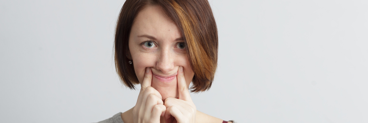Woman using her fingers to make her mouth smile
