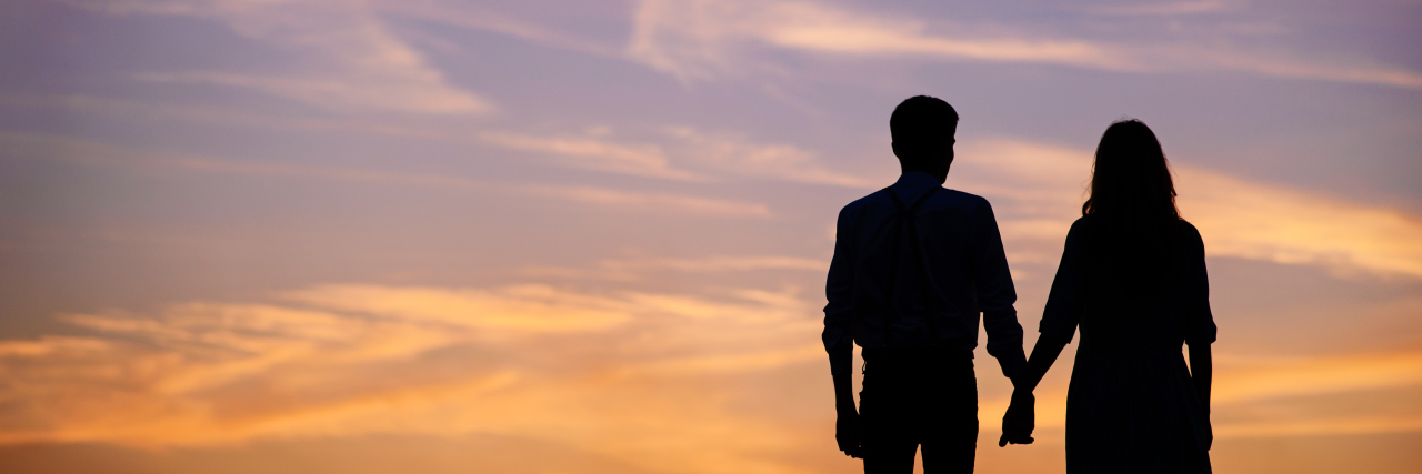 Supporting a Spouse With Lupus Couple holding hands at sunset.