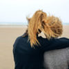 Back view of senior and young woman looking at sea on the beach in autumn