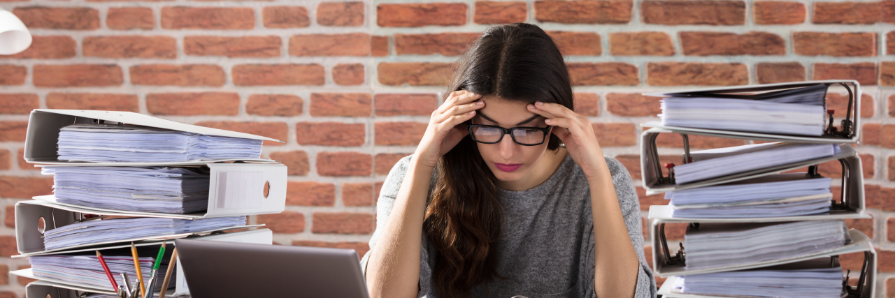 Applying for Social Security Disability With Chronic Migraine Tired woman with piles of paperwork.