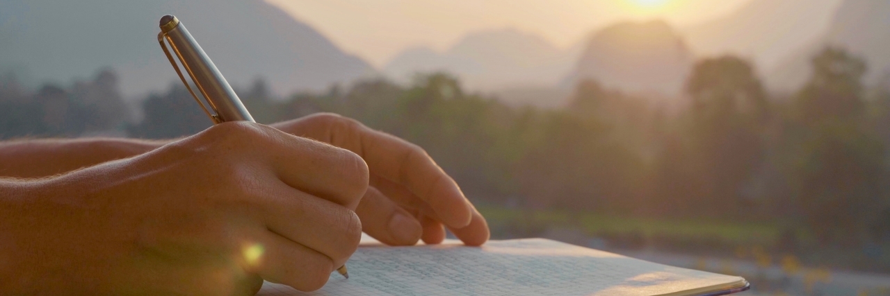 Young woman writing at sunset.