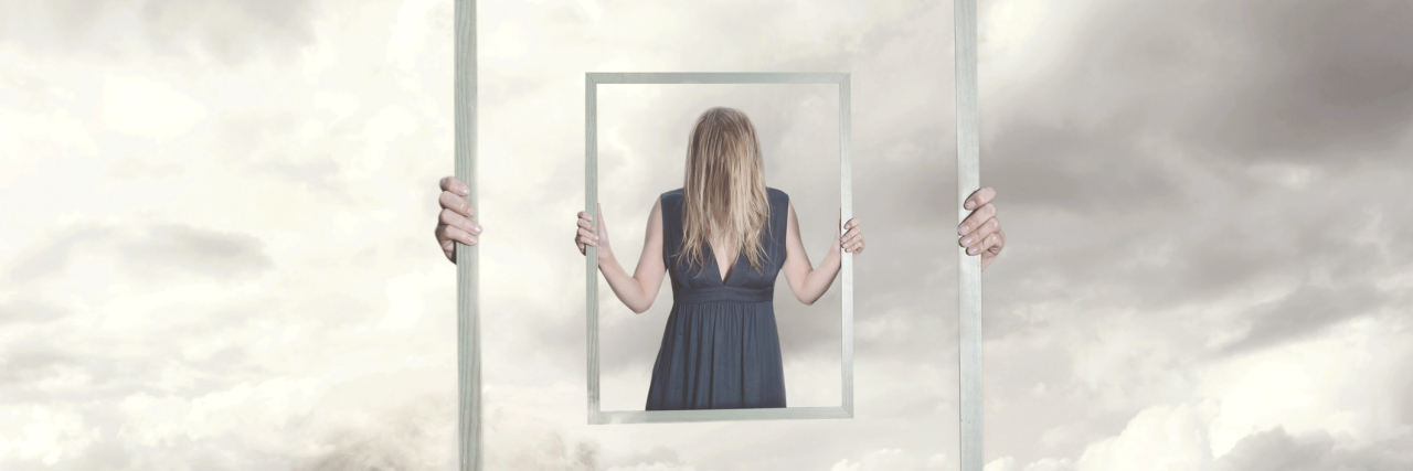 When You Have a Fear of Becoming Seriously Ill With Anxiety A woman holds a mirror with her hair covering her face.