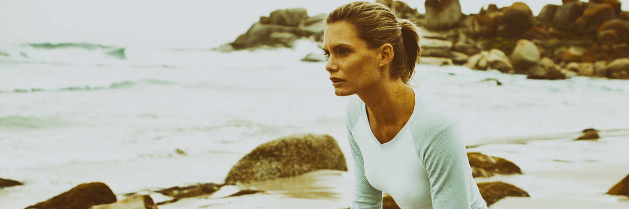 Adjusting to Life Changes as an Athlete With Ehlers-Danlos Syndrome Woman on the beach holding her knee brace.