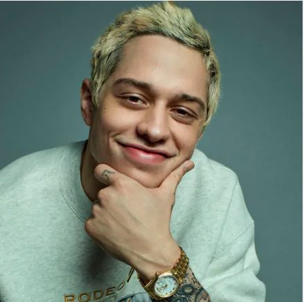 Pete Davidson with grey sweatshirt and hand on chin