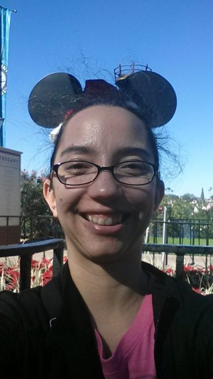 Woman smiling selfie wearing Mickey Mouse ears at Disneyland