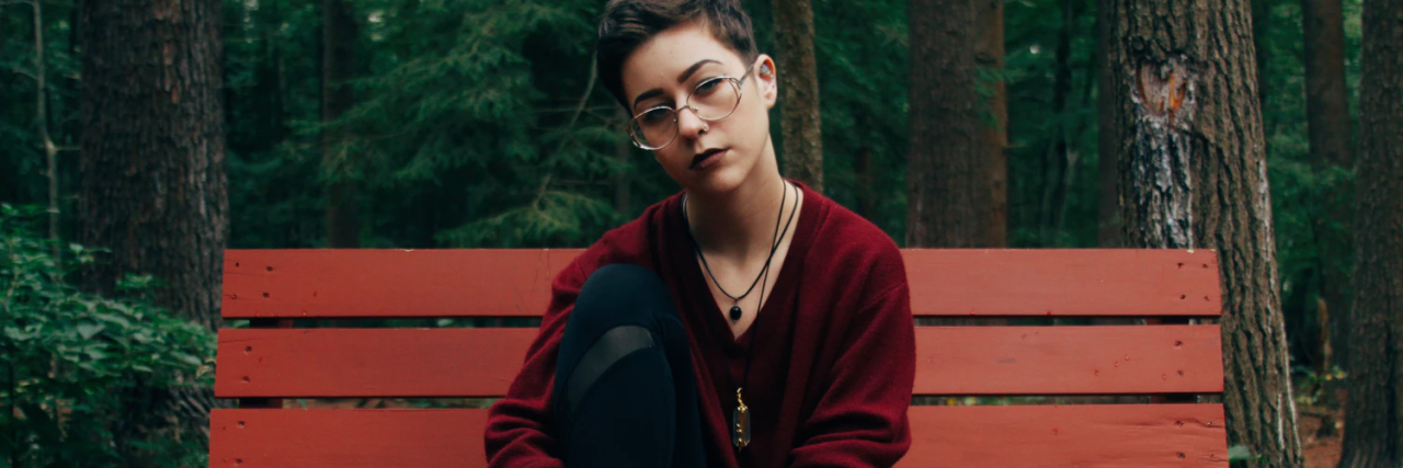 Feeling Emotionally Exhausted as an Empath in the LGBTQIA+ Community photo of person with short hair sitting on bench in forest looking into camera