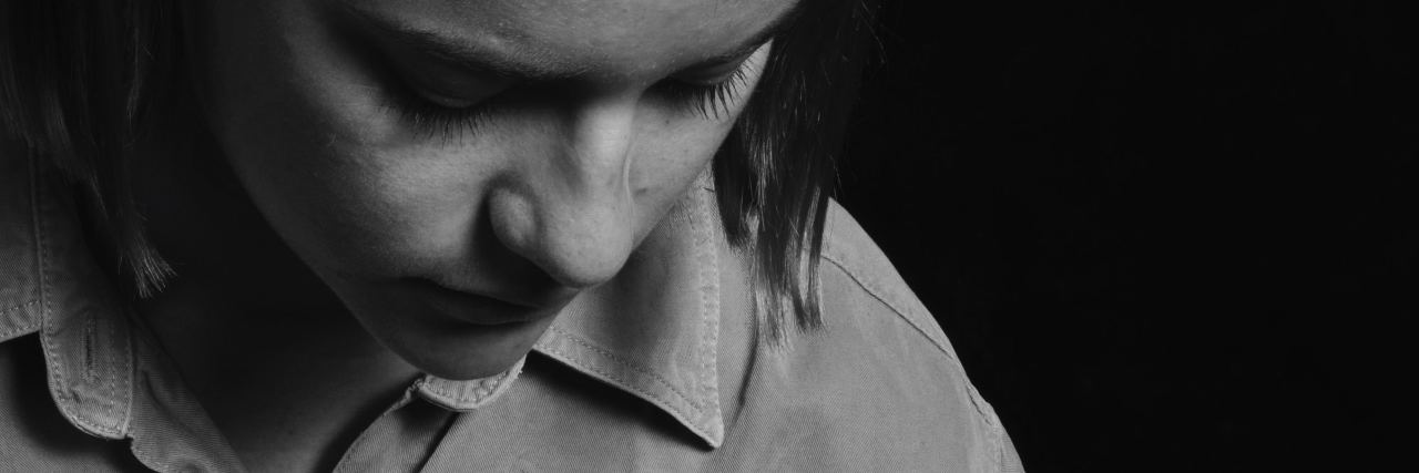 Struggling With Survivor's Guilt During Suicide Prevention Days black and white photo of woman holding flower petals and looking down at them