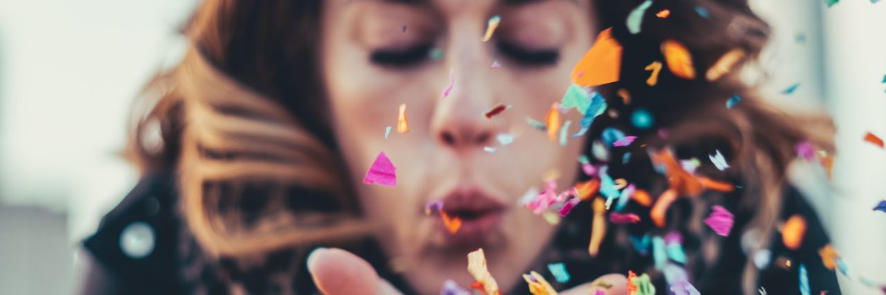 Hiding My Lyme Disease and Finally Talking About It close up photo of woman blowing confetti