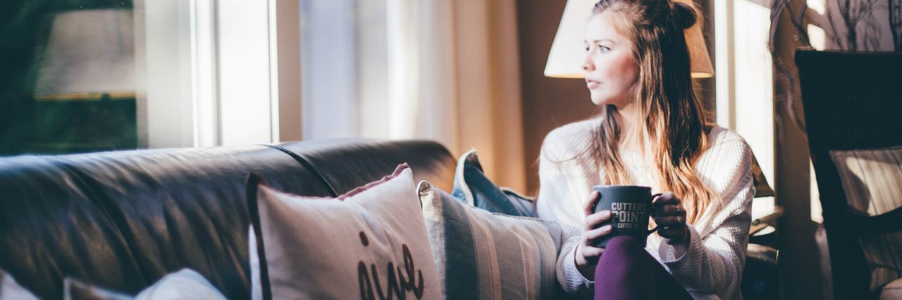 The Stigma I've Seen Toward Mental Illness While Working in the ER photo of woman sitting on couch looking out of window in morning light, holding mug