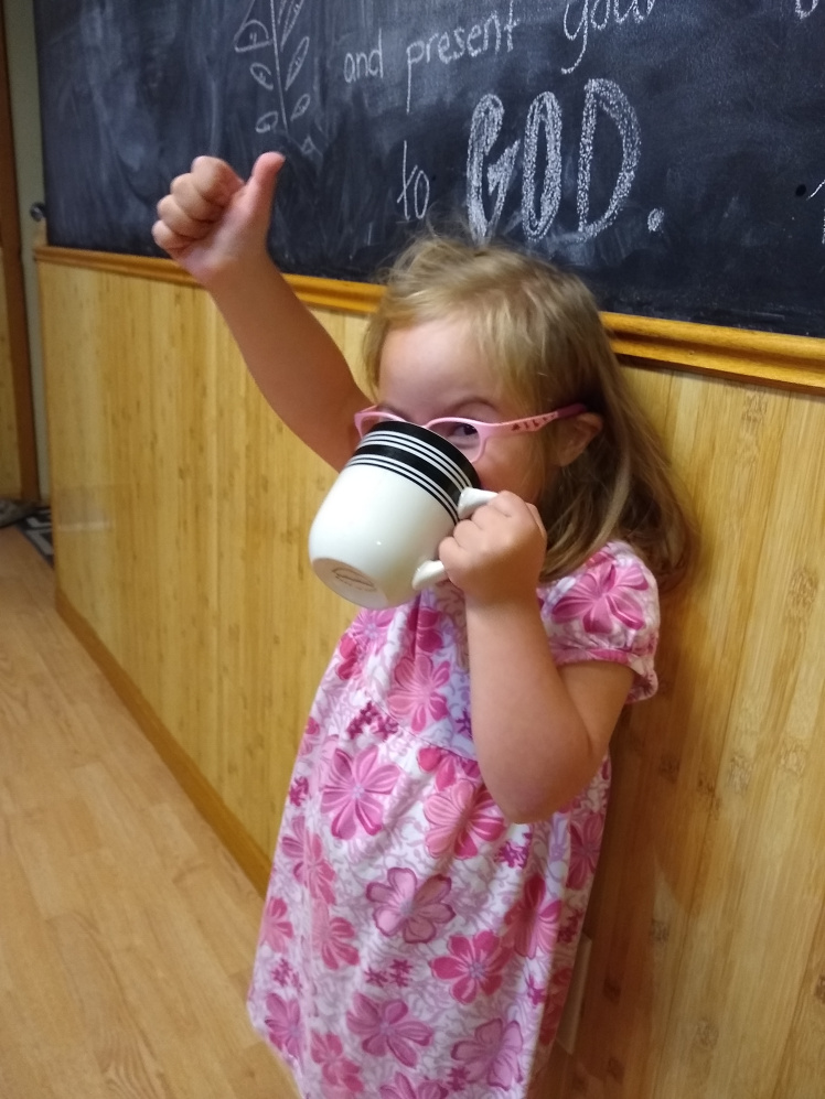 Willow drinking from a mug and giving thumbs up.