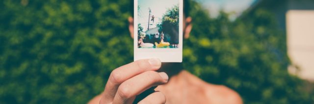 photo of man holding polaroid photo of himself jumping into a pool from a high place