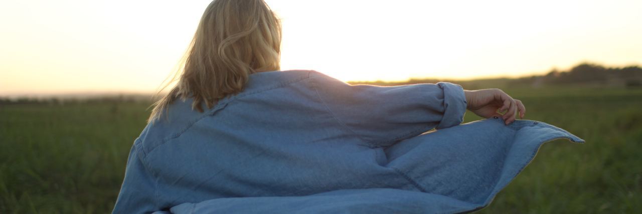 Positives After a Mental Breakdown photo of blonde woman in field with window billowing shirt and sun behind her