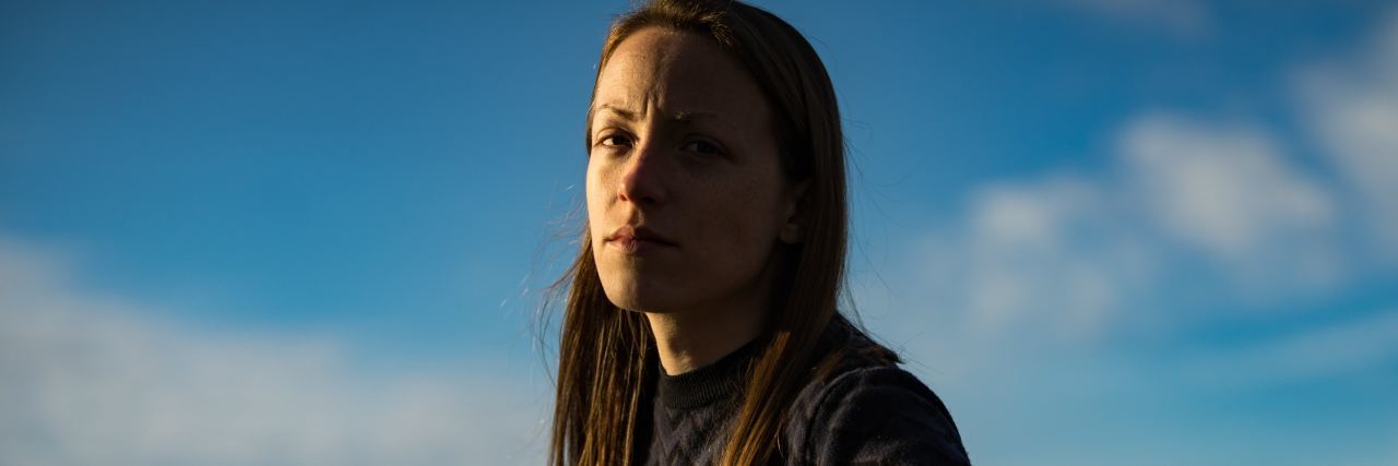 photo of woman against blue sky looking serious into camera