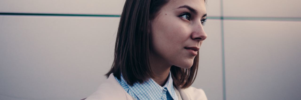 Tips to Be Prepared for College With a Mental Illness photo of young woman with dark hair standing with white wall behind her