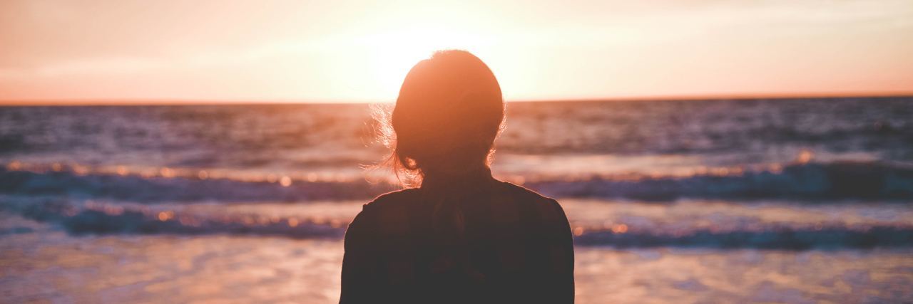 How I Was 'Manipulated' Into Trying Heroin photo of woman standing on beach looking out at waves at sunrise