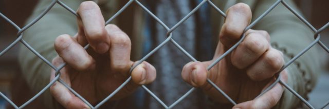 close up photo of woman's hands in chain link fence