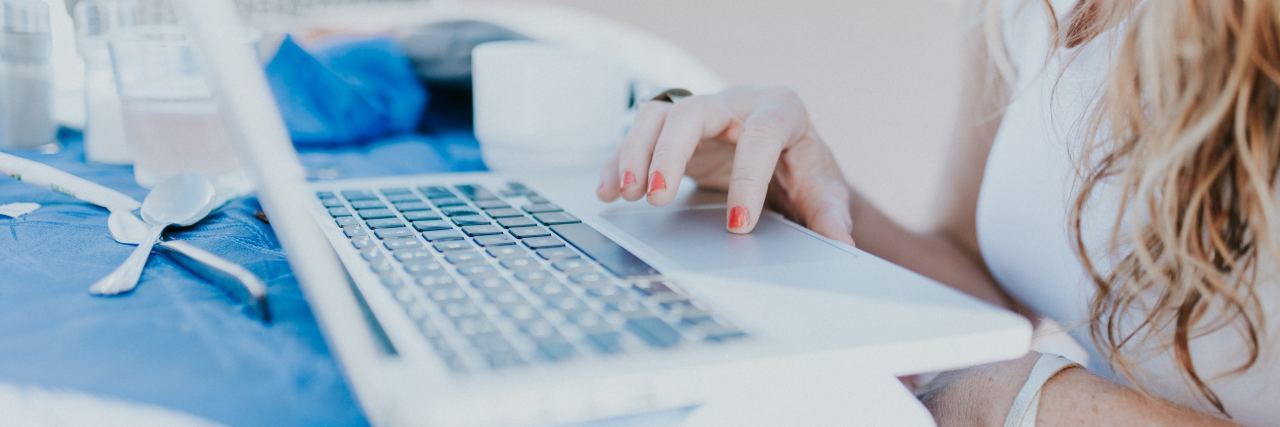 How to Manage Health Care Finances With Chronic Illness photo of woman with laptop, hand across stomach and spoon nearby