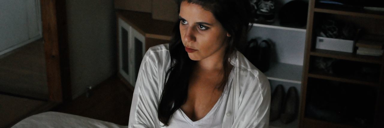 An Example of 'Splitting' in Borderline Personality Disorder photo of woman sitting on bed with arms folded looking annoyed