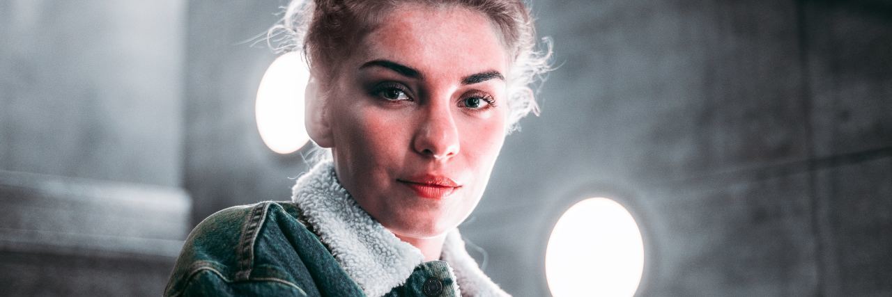 What to Do If You Need to Change Doctors With a Chronic Illness photo of woman looking into camera sitting on stairs with serious expression