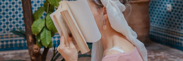 photo of woman covering face with book