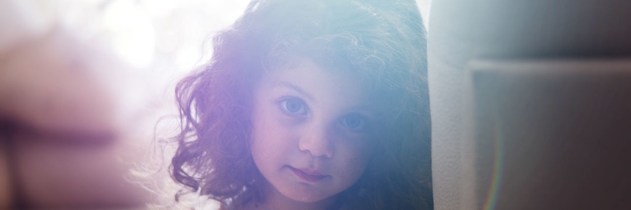 Moving Past Childhood Abuse and Gaslighting, and Towards Understanding Child looking at camera with soft light behind her