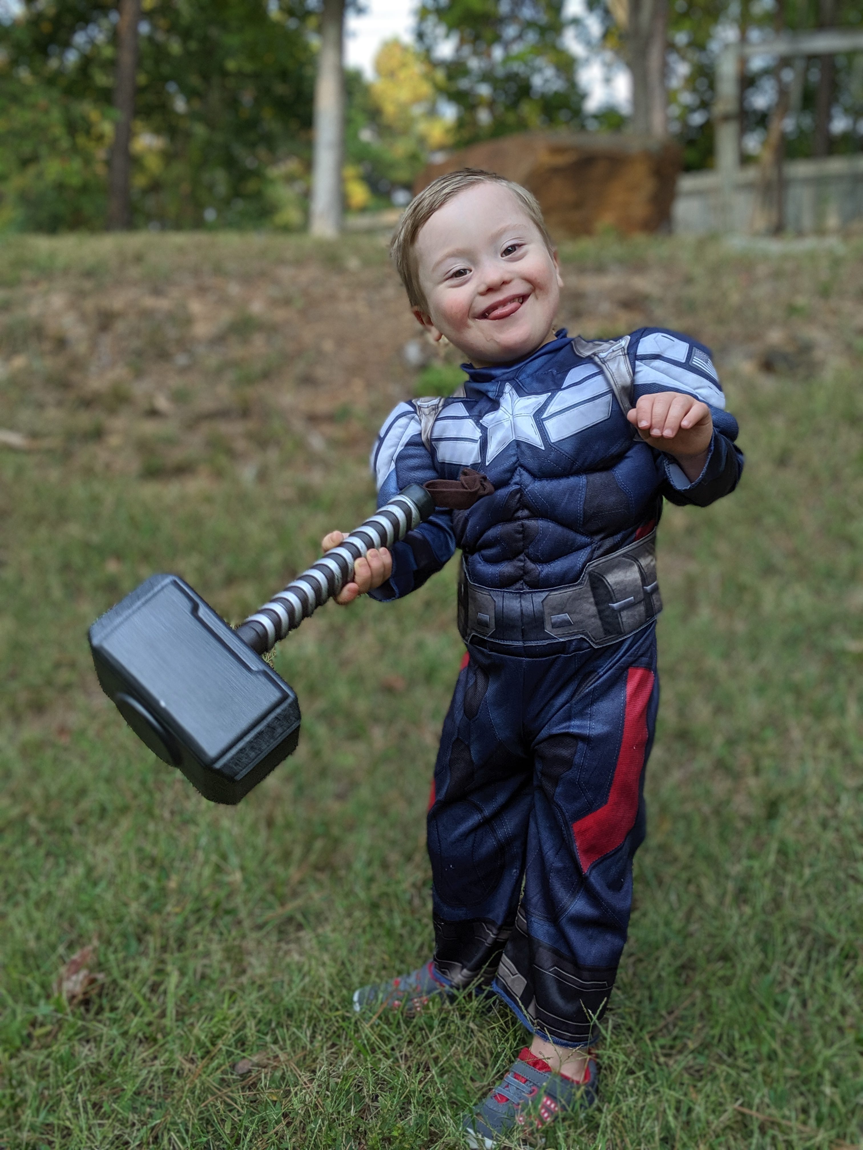 Adam's son who has Down syndrome dressed as Captain America holding Thor's hammer.