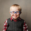 Kat's son, a boy with Down syndrome wearing blue glasses and a sweater vest.