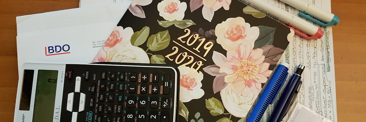 How Having Bipolar Disorder Affects Your Finances A stack of papers, a calculator and a planner on a table