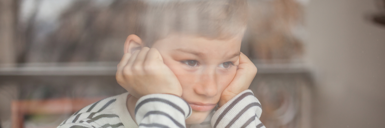 How Inclusion Can Help Stop Bullying of Autistic Kids Sad boy looking through window.